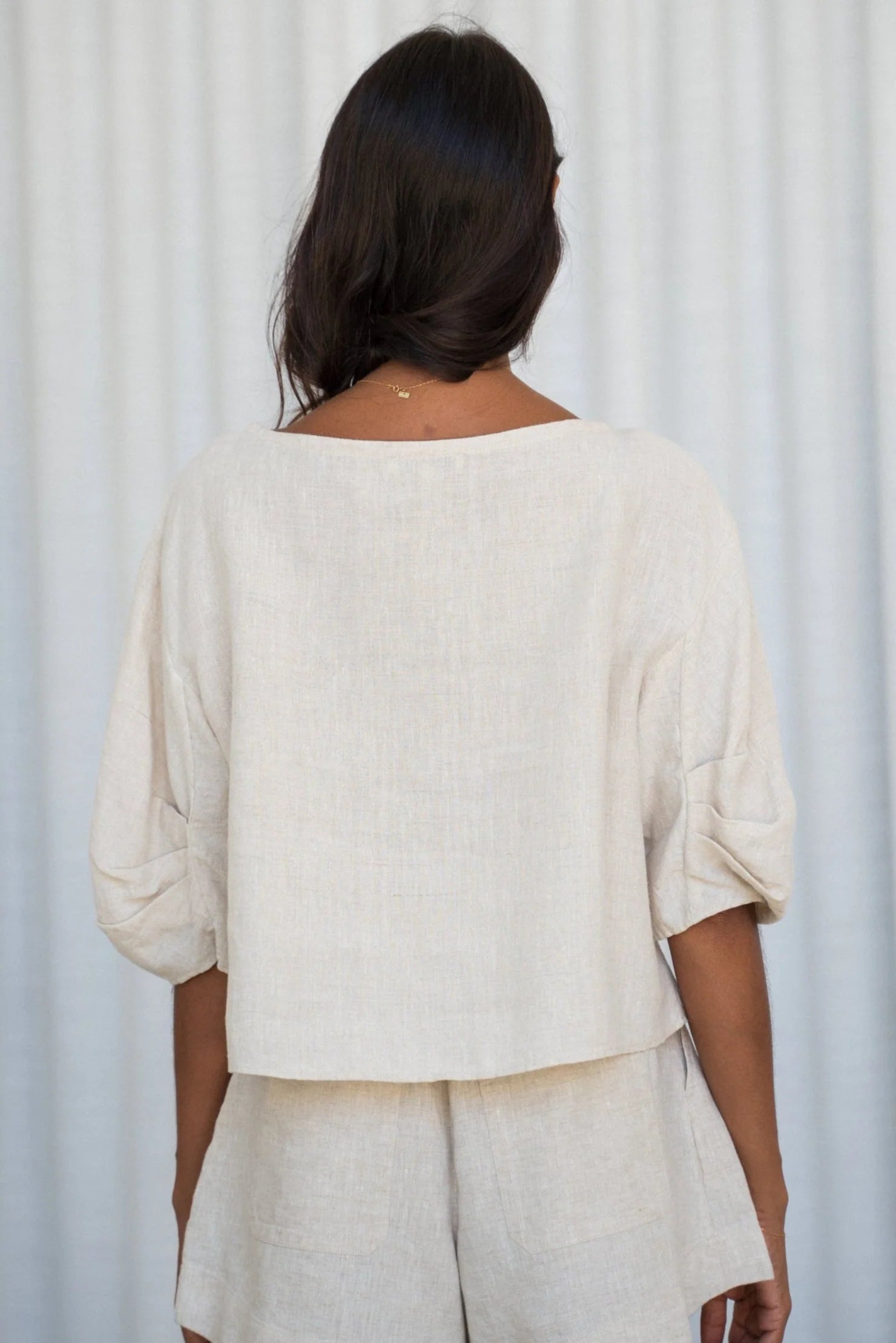 Person wearing a beige outfit against a white curtain background rear view from Lilly Pilly