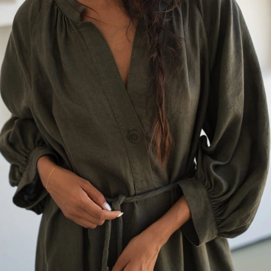 Woman wearing a green linen dress with long sleeves in an indoor setting