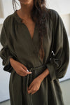 Woman wearing a green linen dress with long sleeves in an indoor setting