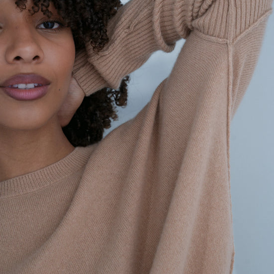 Woman wearing a beige sweater with a blurred background