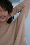 Woman wearing a beige sweater with a blurred background