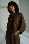 Woman wearing a brown outfit against a plain background