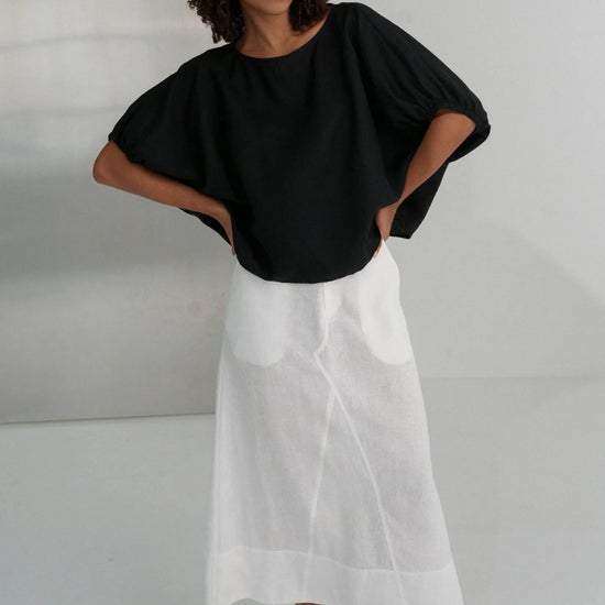 Person wearing a black top and white skirt against a plain background from Lilly Pilly