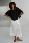 Person wearing a black top and white skirt against a plain background from Lilly Pilly