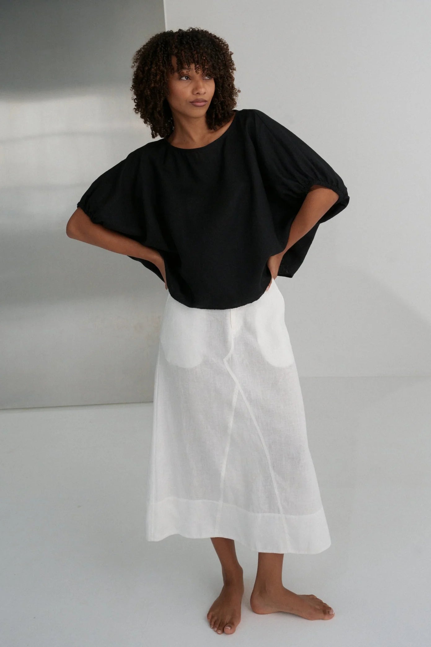 Person wearing a black top and white skirt against a plain background from Lilly Pilly