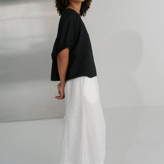 Person wearing a black top and white pants against a plain background from Lilly Pilly