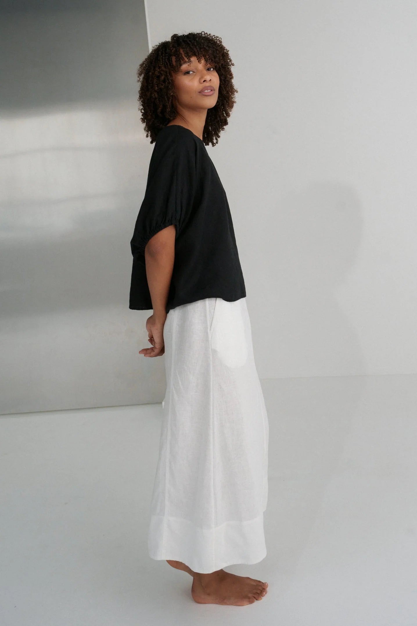 Person wearing a black top and white pants against a plain background from Lilly Pilly