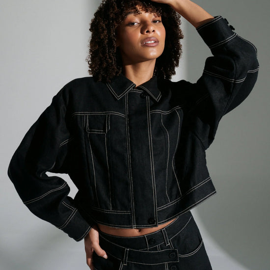 Woman wearing a black linen jacket against a gray background