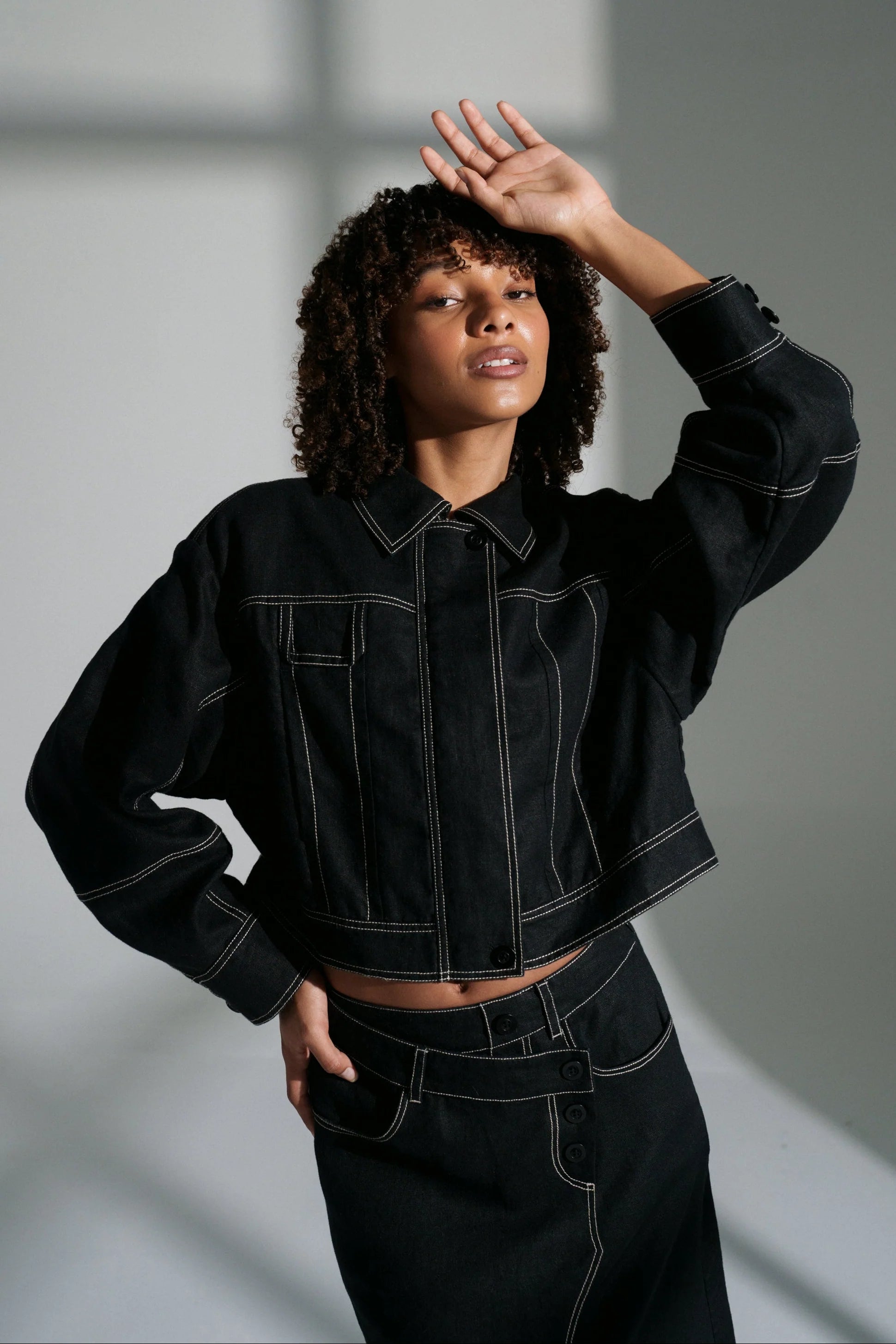 Woman wearing a black linen jacket against a gray background