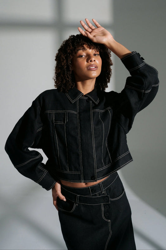 Woman wearing a black linen jacket against a gray background