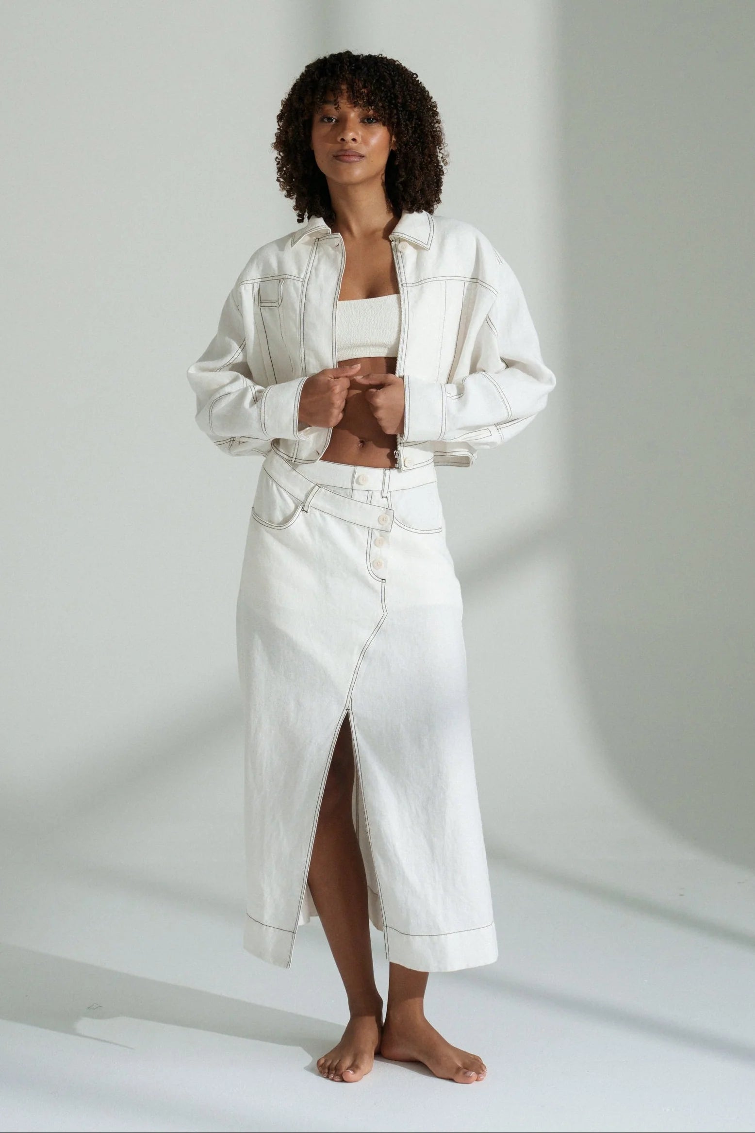 Woman wearing a white linen outfit on a plain background