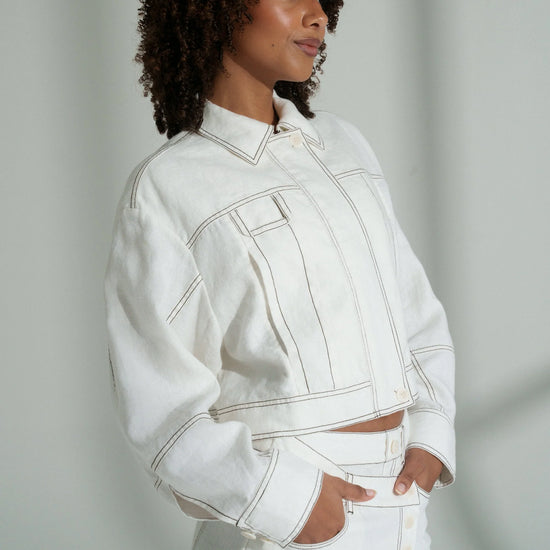 Person wearing a white linen outfit against a plain background