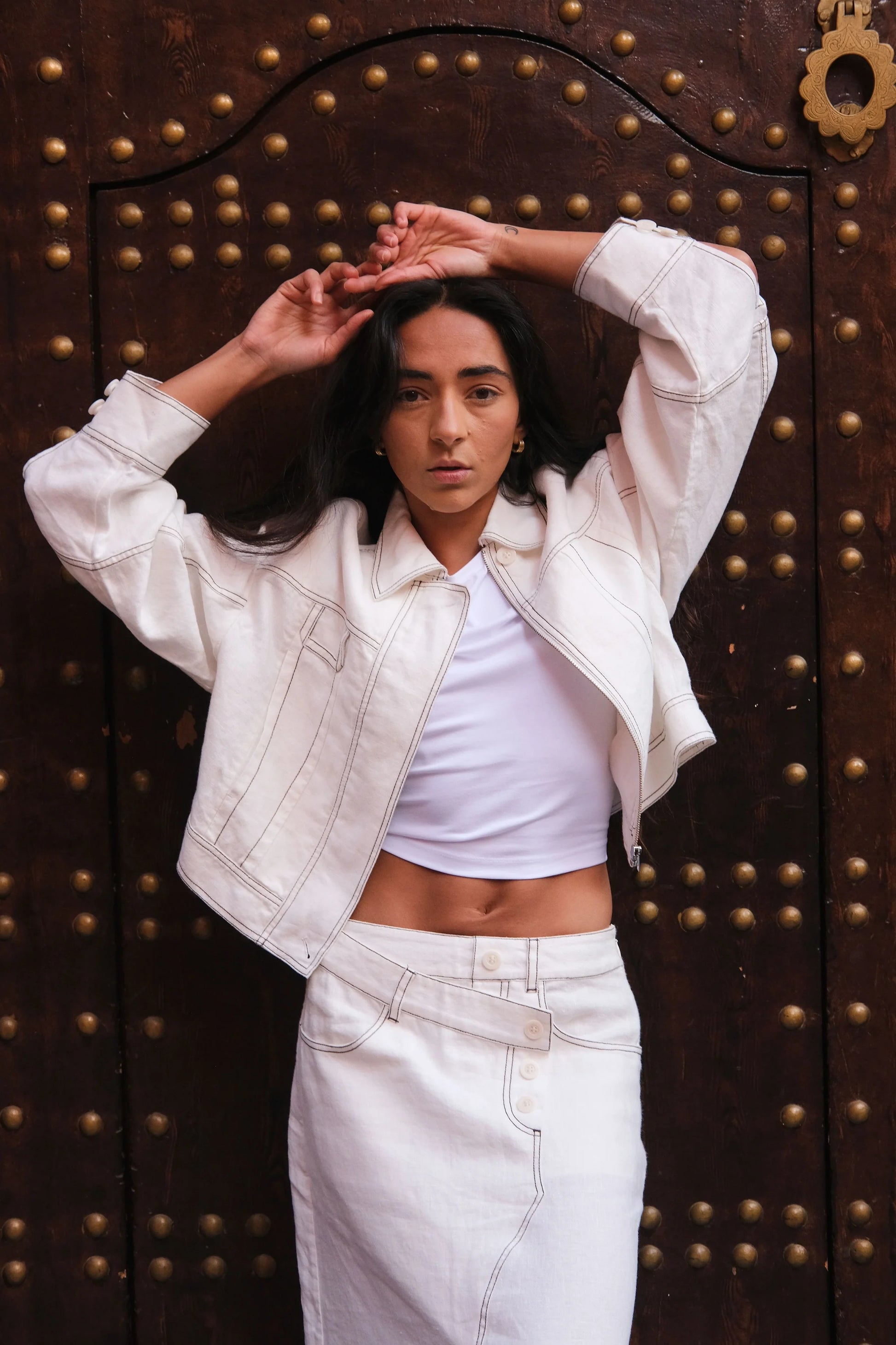 Person wearing a white outfit in front of a textured brown door