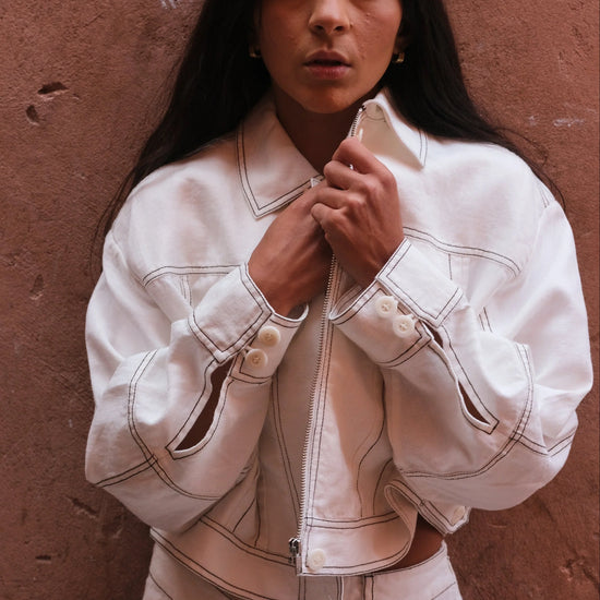 Person wearing a white jacket against a brown wall