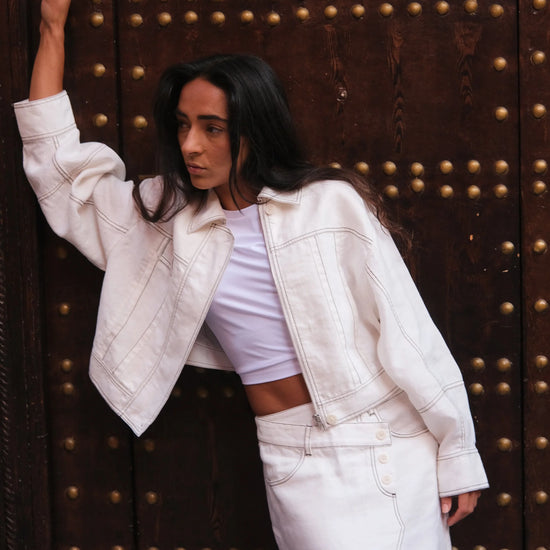 Woman in a white outfit posing in front of a large ornate door.