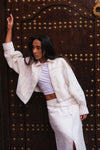 Woman in a white outfit posing in front of a large ornate door.