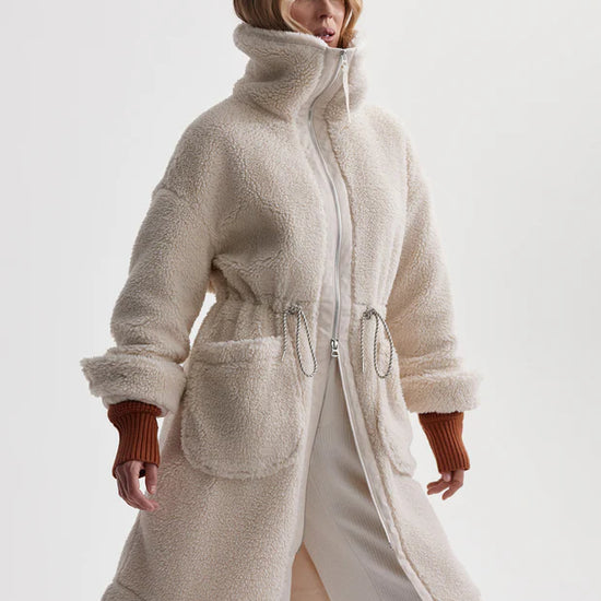 cream sherpa coat with high neck, 2 large patch pockets and drawstring waist side view 