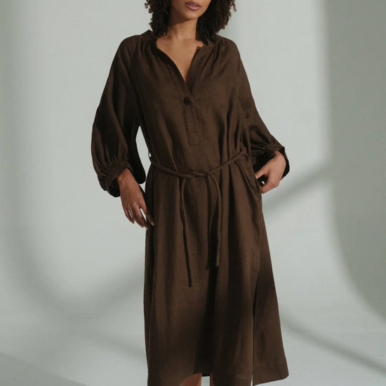 Woman wearing a brown linen dress against a plain background