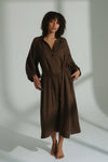 Woman wearing a brown linen dress against a plain background