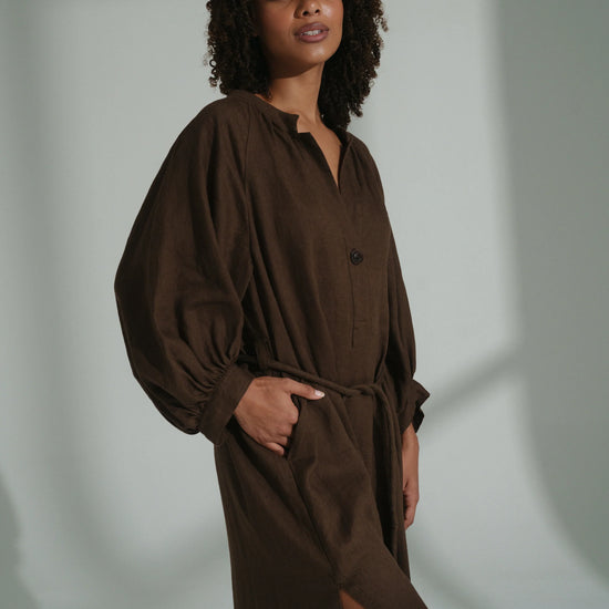 Woman wearing a brown linen dress against a neutral background