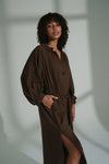Woman wearing a brown linen dress against a neutral background