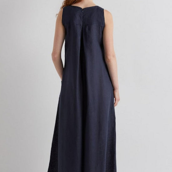 Woman wearing a long navy jumpsuit on a plain background