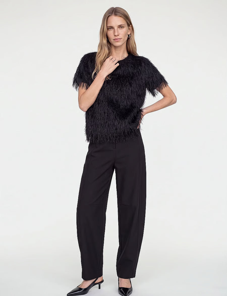 Model wearing a black feather-trimmed short-sleeve top, black wide-leg trousers, and black pointed heels.