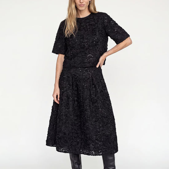 model wearing a black sequin skirt with a matching top and black boots 