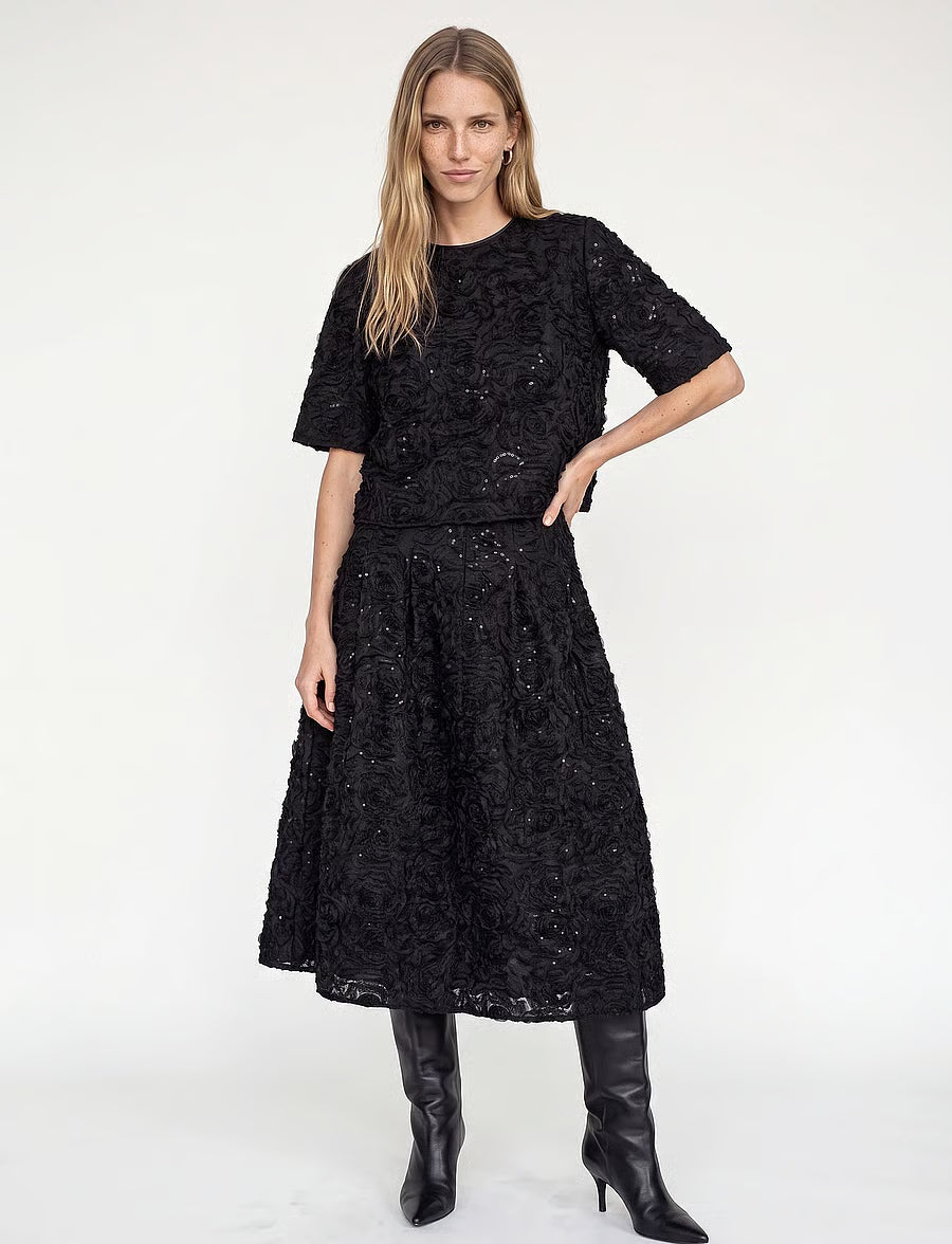 model wearing a black sequin skirt with a matching top and black boots 