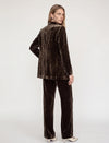 Model wearing a brown velvet suit facing backwards on a plain background