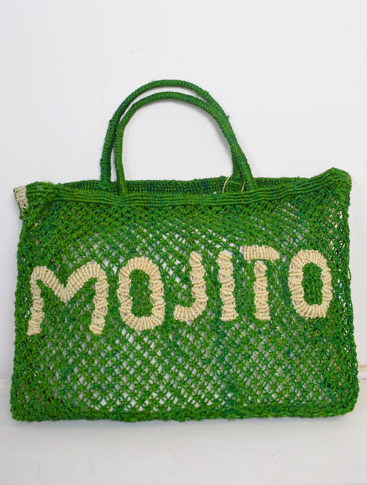 Green woven bag with neutral writing