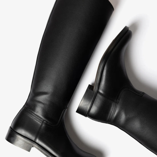 A pair of black leather knee-high riding boots, one shown from a side profile and the other from a rear three-quarter angle, on a clean white background.