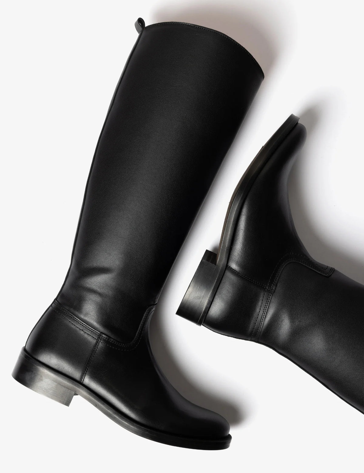 A pair of black leather knee-high riding boots, one shown from a side profile and the other from a rear three-quarter angle, on a clean white background.