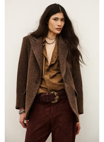 A model wearing a brown textured tweed blazer over a brown button-up shirt, paired with dark burgundy trousers and a dark brown braided belt with a gold buckle, set against a plain off-white background.