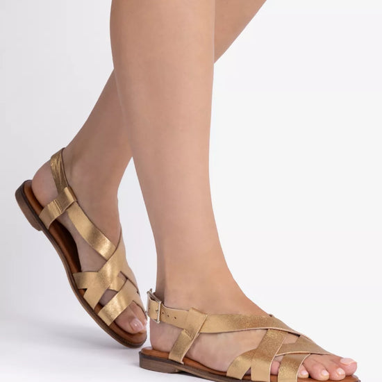 Gold sandals worn with sheer stockings on a white background