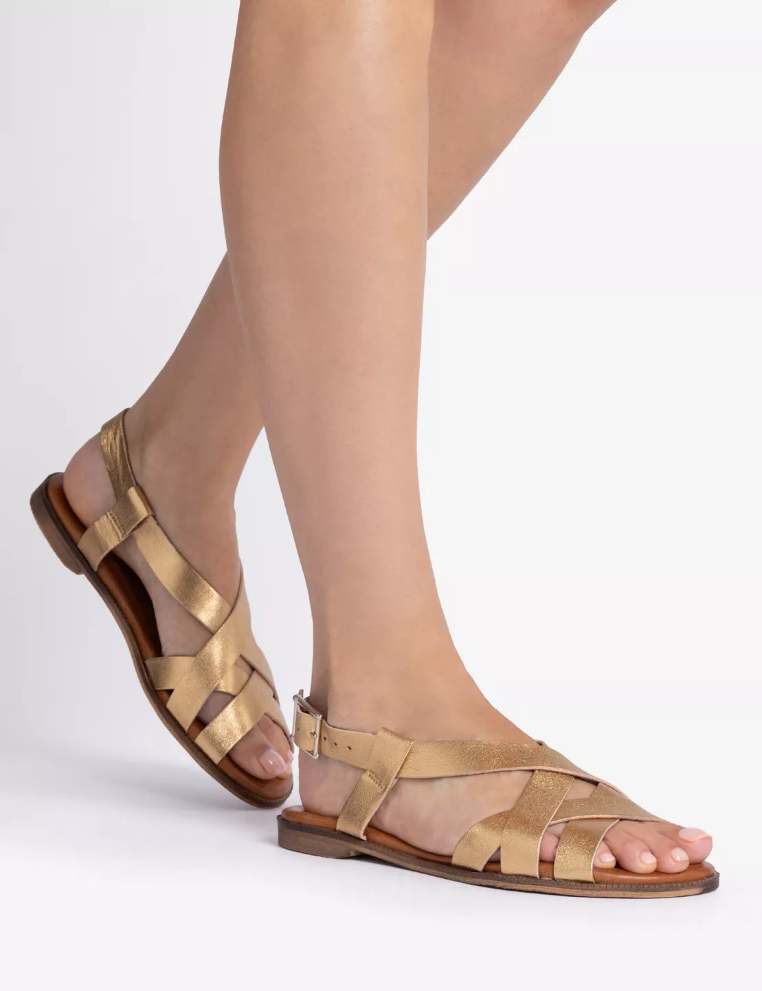 Gold sandals worn with sheer stockings on a white background
