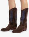 woman wearing Brown cowboy boots with blue embroidery on white background