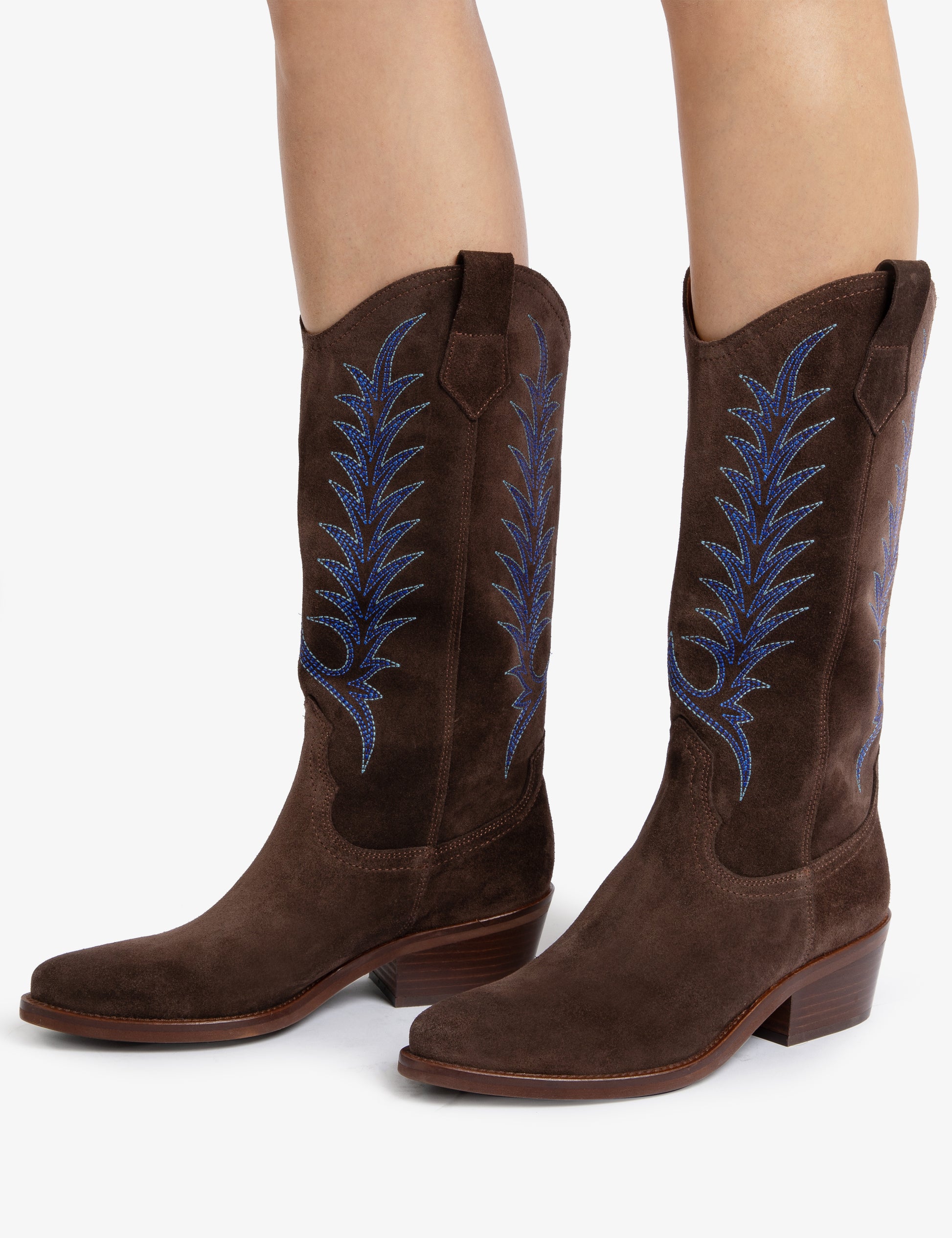 woman wearing Brown cowboy boots with blue embroidery on white background