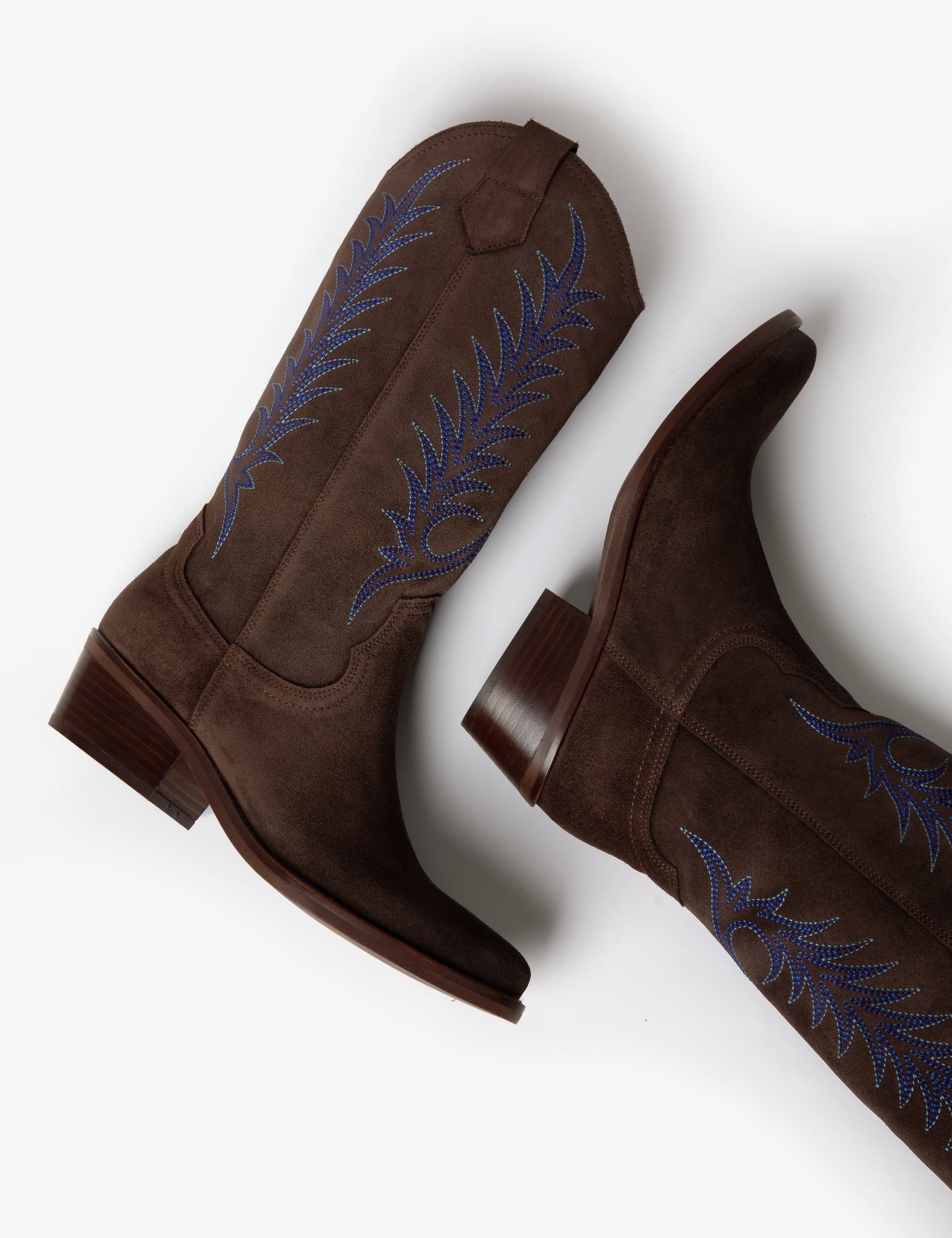 Brown cowboy boot with blue embroidery on white background laying down