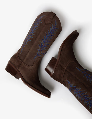 Brown cowboy boot with blue embroidery on white background laying down