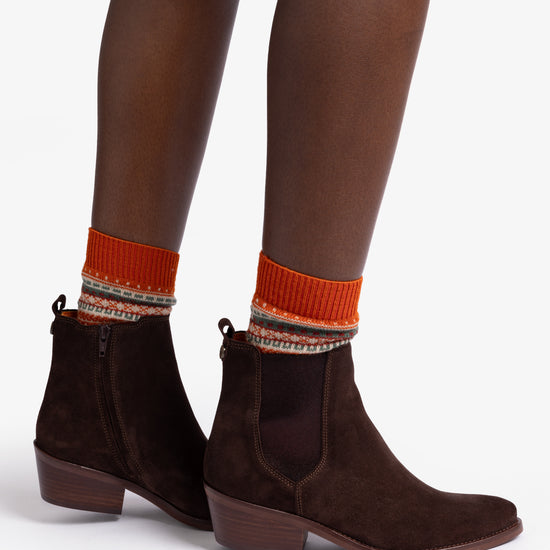 woman wearing Pair of brown suede ankle boots with orange lining on white background