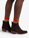 woman wearing Pair of brown suede ankle boots with orange lining on white background