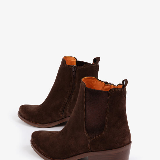 Pair of brown suede ankle boots with orange lining on a white background