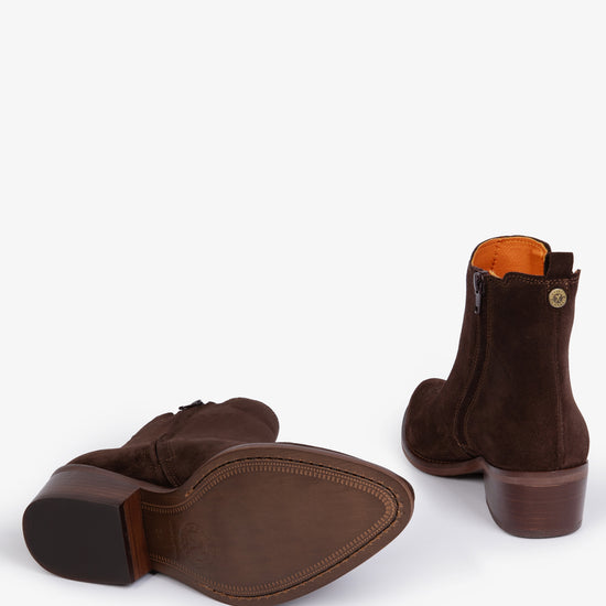 Pair of brown suede ankle boots with orange lining laying down on a white background