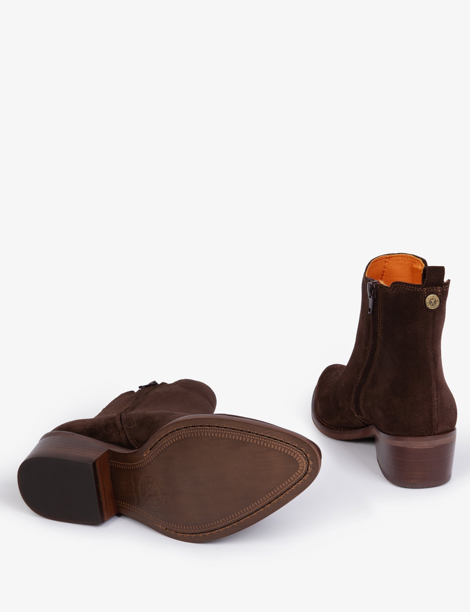 Pair of brown suede ankle boots with orange lining laying down on a white background
