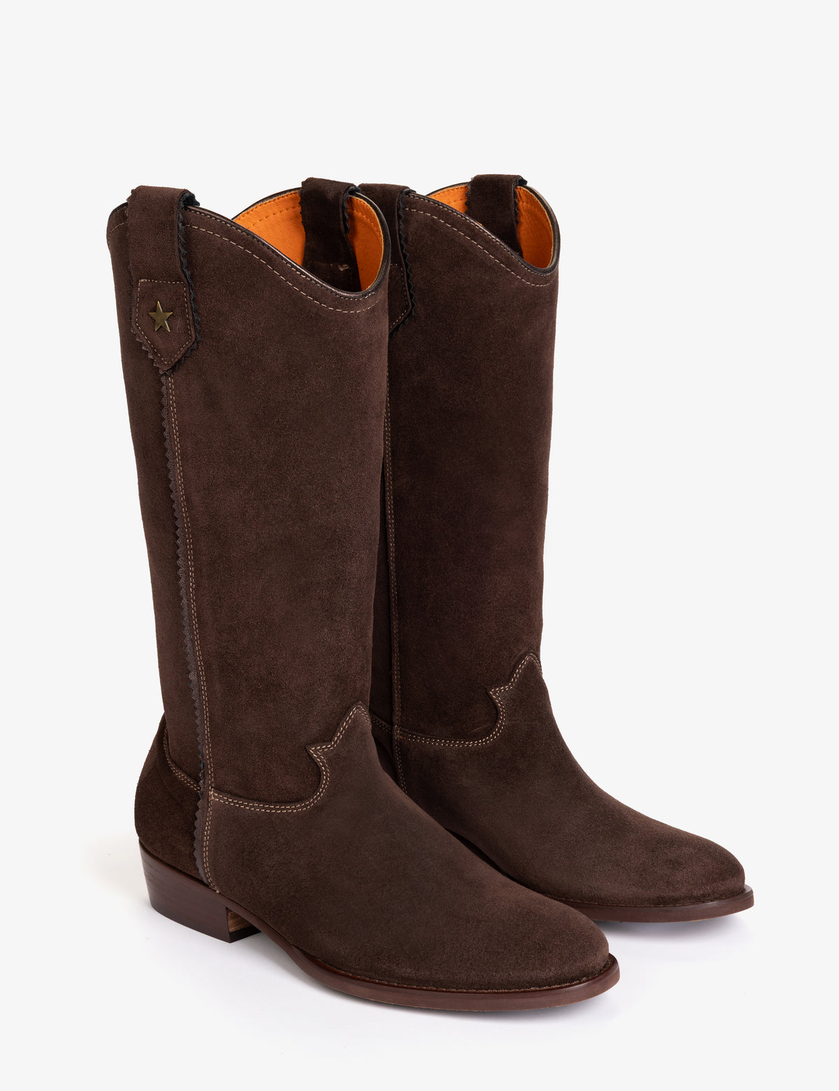 A pair of dark brown suede cowboy boots with a low block heel and a small gold star detail on the pull tab, shown against a plain white background.