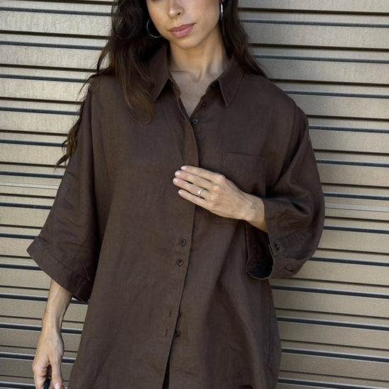 Woman wearing a brown outfit against a metallic background
