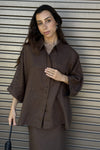 Woman wearing a brown outfit against a metallic background