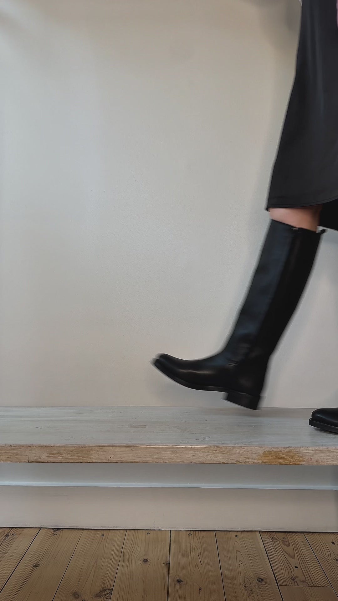 Model wearing tall equestrian style black leather boots shown at different angles. 