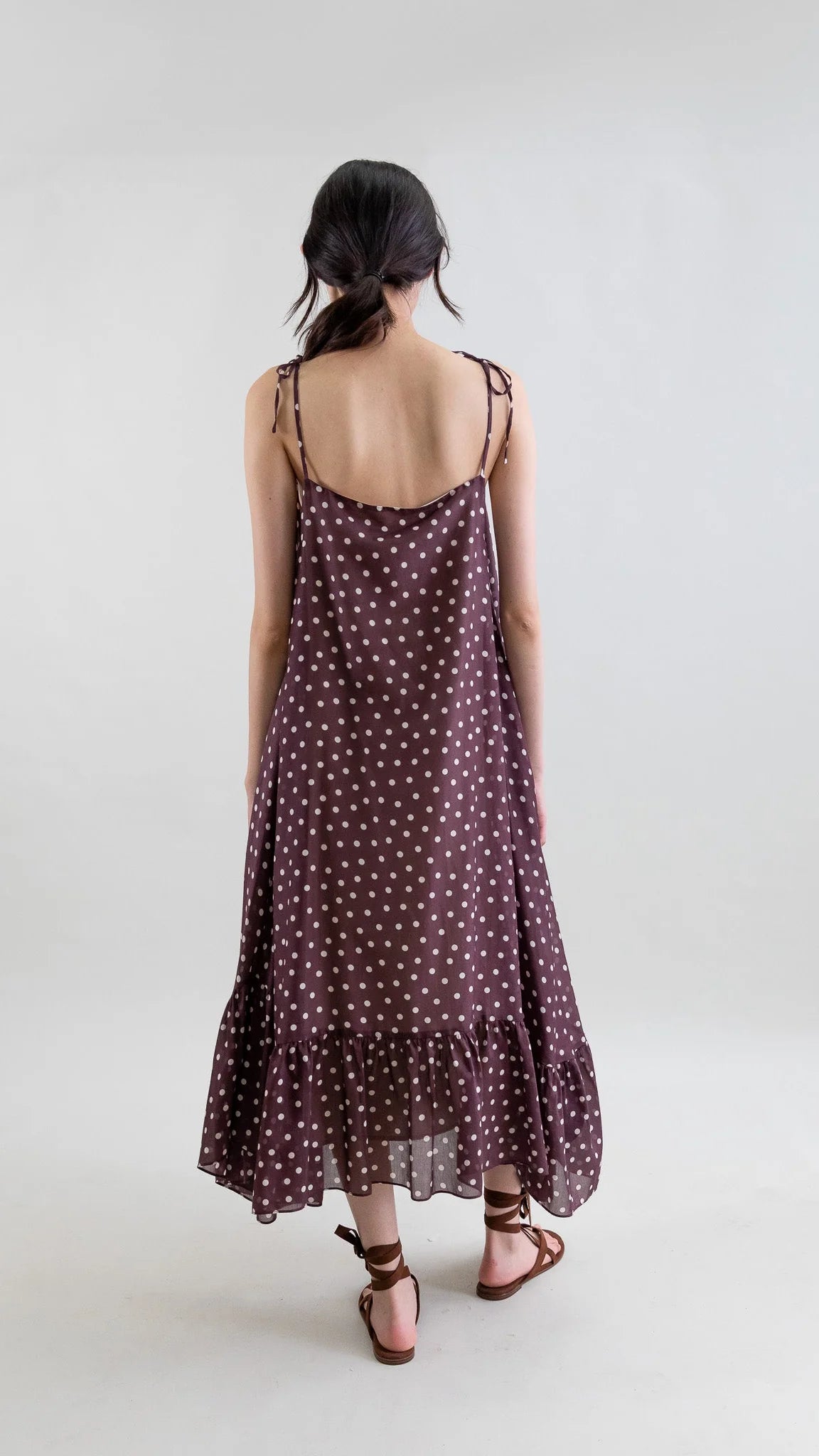 Woman wearing a polka dot dress on a plain background